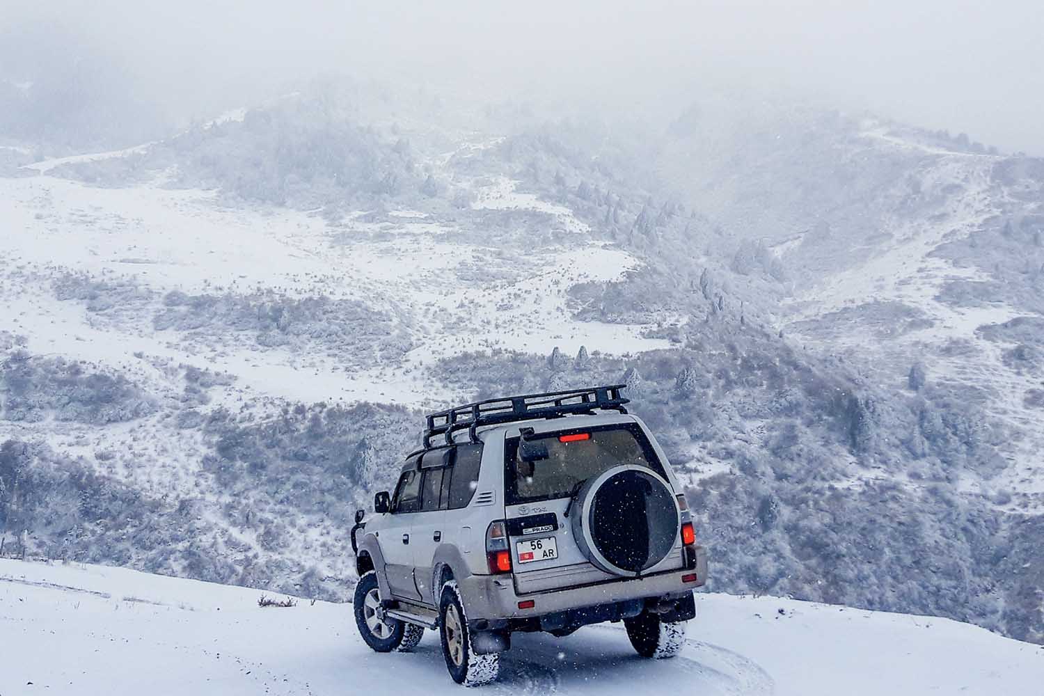 A car driving through snow on a mountain.