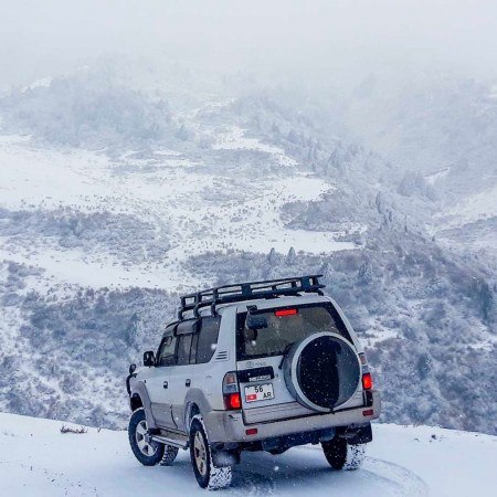 A car driving through snow on a mountain.