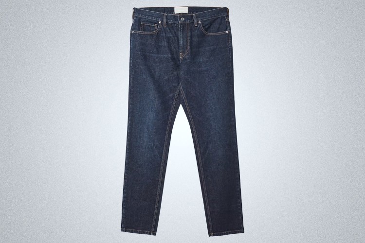 A pair of dark blue Everlane denim jeans on a grey background