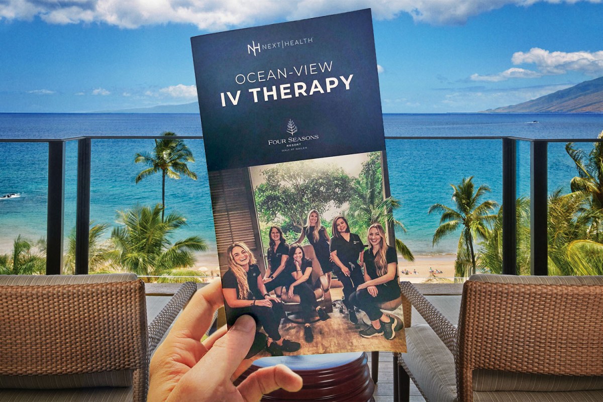 A Next Health brochure for "Ocean-View IV Therapy" held in a hand at the Four Seasons Maui at Wailea