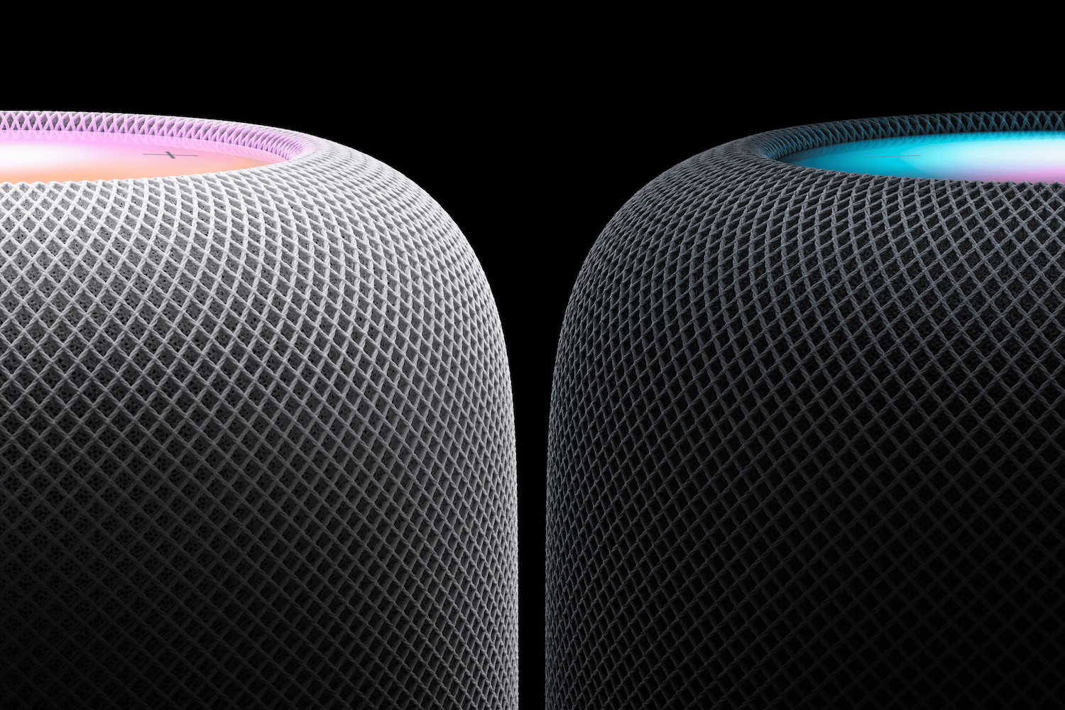 two Apple homepods on a black background