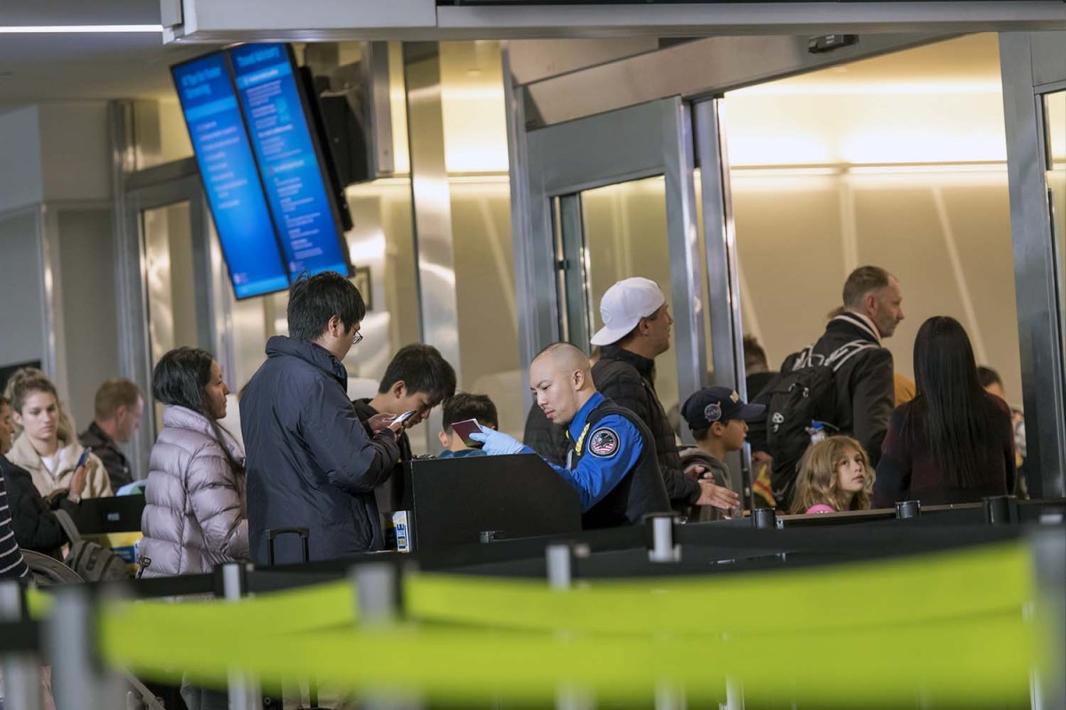 A Transportation Security Administration (TSA) agent views a traveler's passport at a checkpoint at San Francisco International Airport