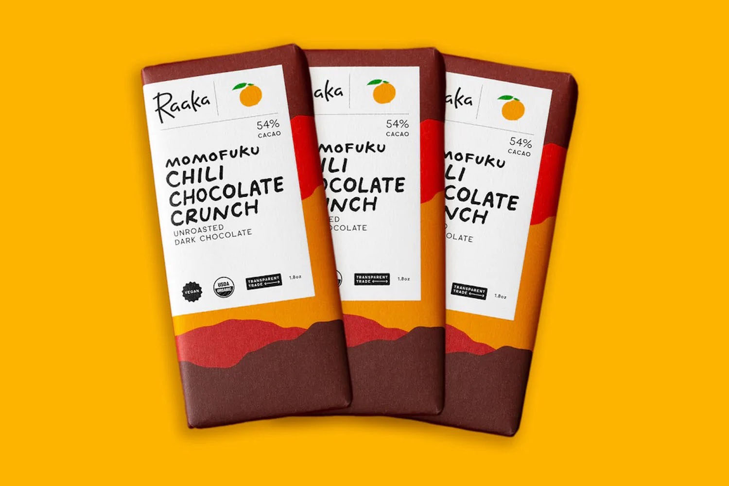 Three bars of Momofuku x Raaka Chocolate Company Chili Chocolate Crunch on an orange-yellow background