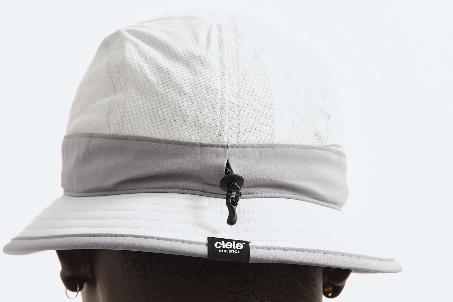 a model wearing a silver Reigning Champ x Ciele hat on a white background
