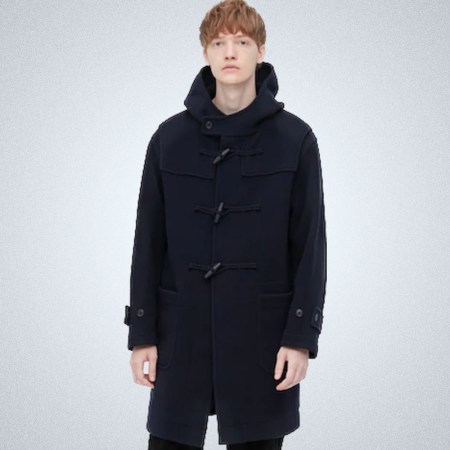 A model in a navy Uniqlo Duffle Coat on a grey background
