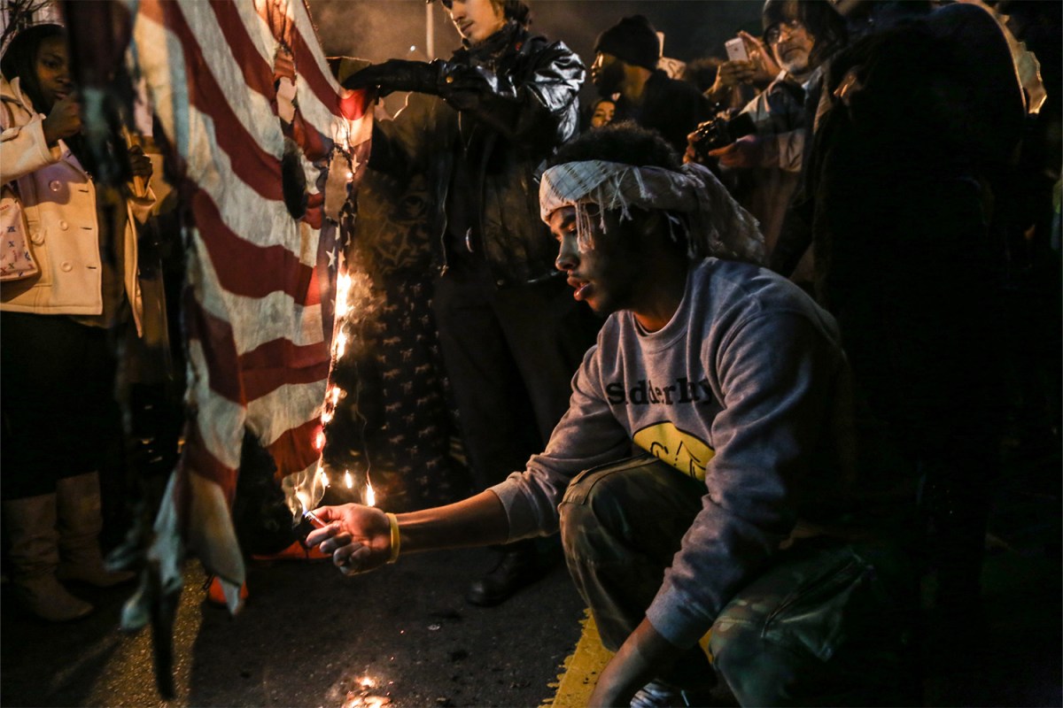 A black lives matter protester burns a flag in Chinatown, Washington, DC following the verdict to not indict officer Daren Wilson after the shooting and subsequent death of Michael Brown. -June 20th, 2014.
