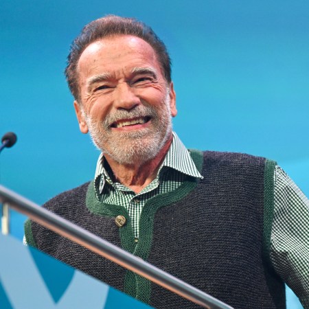Arnold Schwarzenegger grinning at a podium.