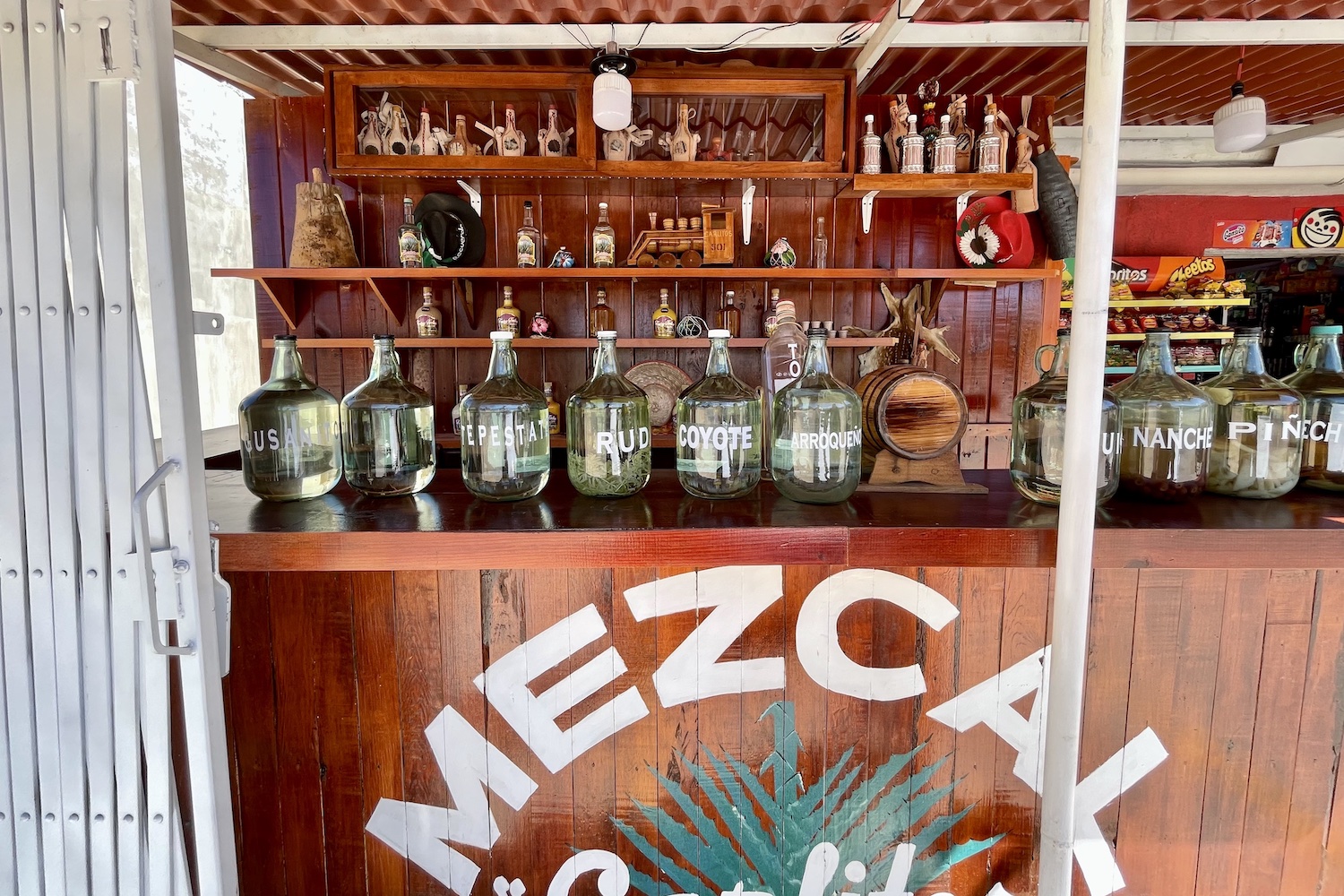jogs of mezcal sitting on a wooden bar at carlitos mezcal