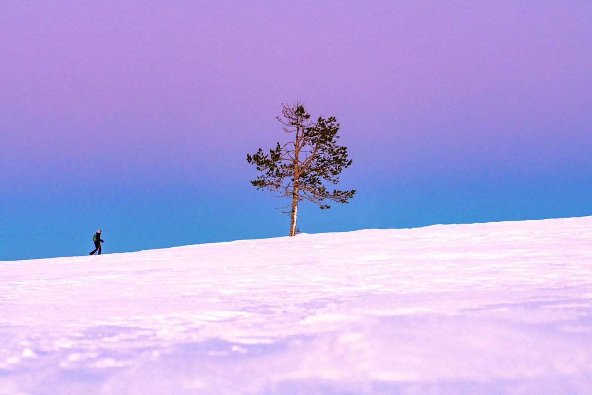 A woman snowshoeing in Finland at dusk.