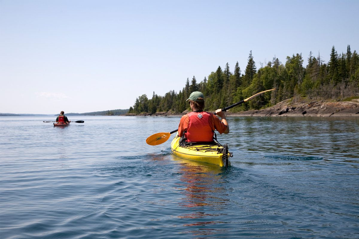 Two people kayaking off the shore of Isle Royale National Park, one of five parks along Lake Superior that plans to decarbonize in order to fight climate change