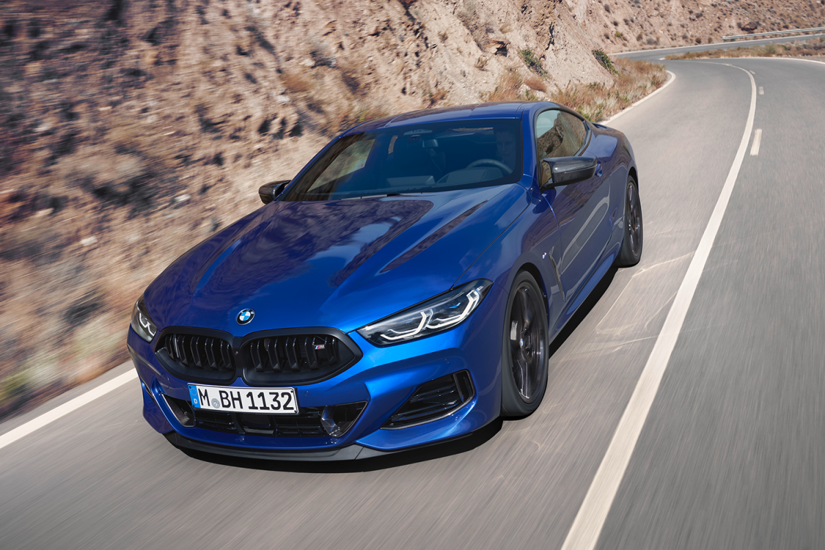 A blue 2023 BMW M850i Coupe, part of the BMW 8 Series, driving down the road. Read our full review of the luxury coupe.
