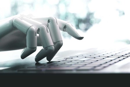 A robot hand using a keyboard. Articles on CNET written by artificial intelligence recently appeared with numerous mistakes.