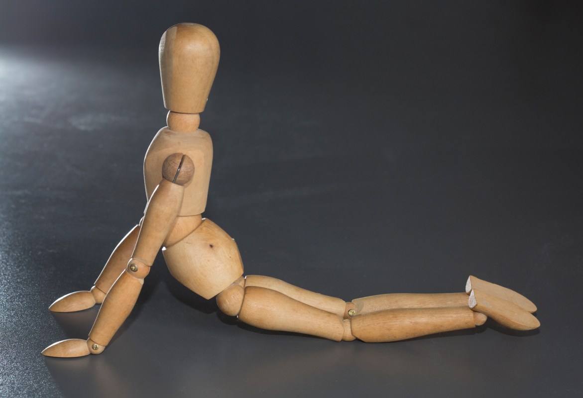 A wooden puppet stretching on the floor