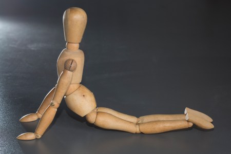 A wooden puppet stretching on the floor