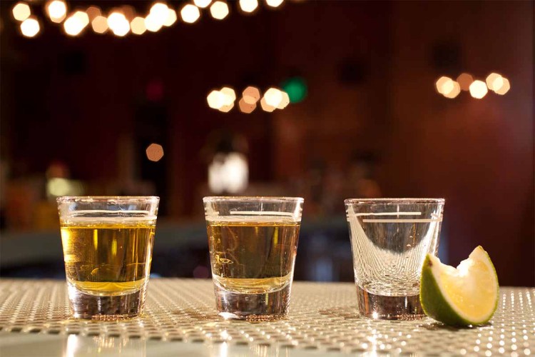 Shots of various types of tequila on bar with lime wedge. While tequila sales continue to shine, other spirits categories are hitting a ceiling.