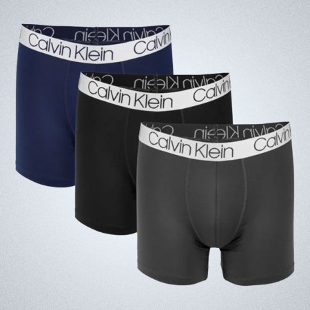 a three back of dark-colored Calvin Klein boxer briefs on a grey background