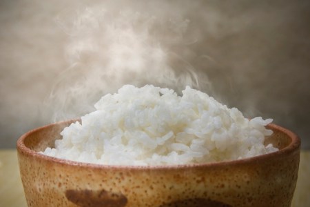 steaming white rice in a brown bowl