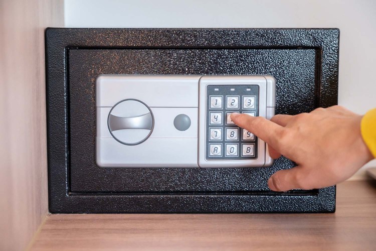A hand typing in a passcode on a hotel safe box. If you've ever forgotten something in a hotel safe, try this travel hack from TikTok.