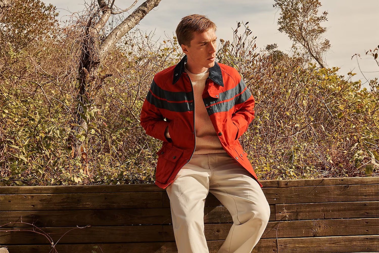 a model in the new J.Crew x Barbour Bedale jacket sitting on a log