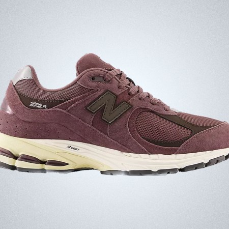 a pair of truffle colored New Balance 2002R sneakers on a grey background