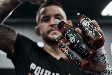 UFC fighter Dustin Poirier holds up his hot sauce line.