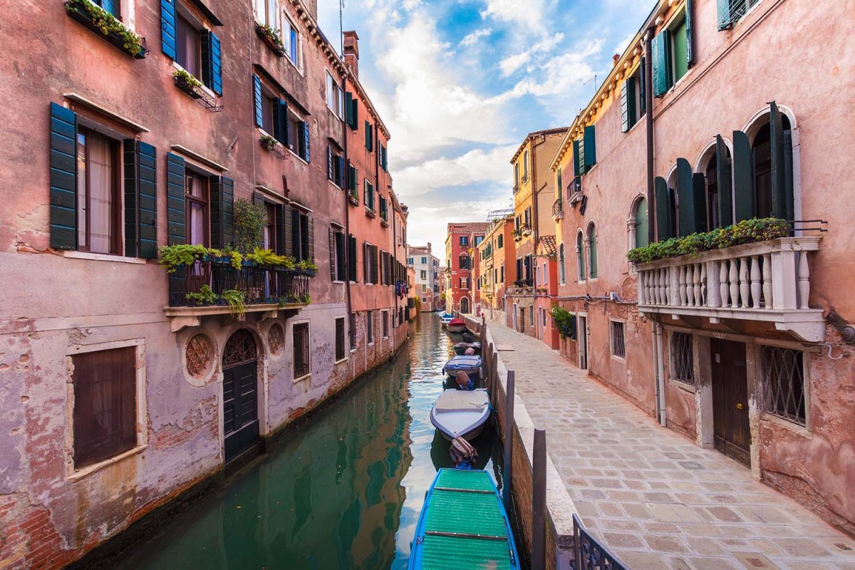 small venice canal with pink buildings on either side