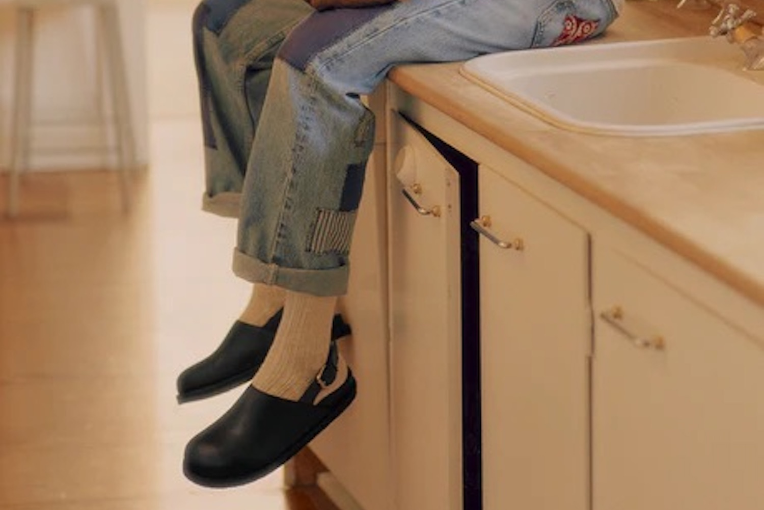 a model in a pair of Vinny's shoes sitting on a kitchen sink