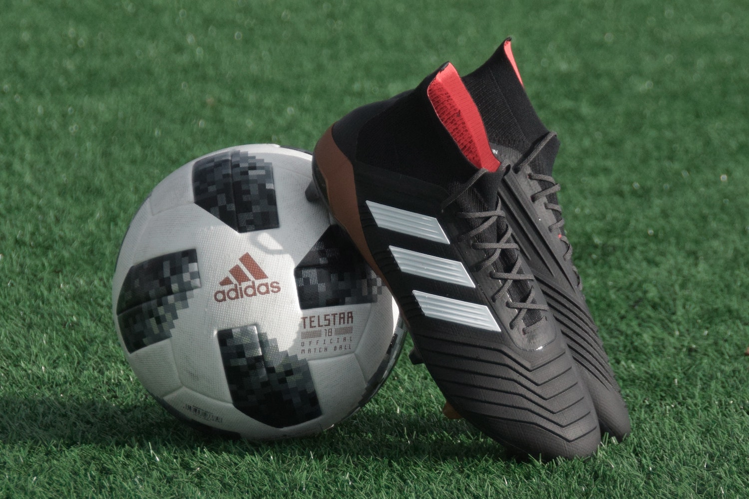 A pair of Adidas soccer cleats lean against a soccer ball.