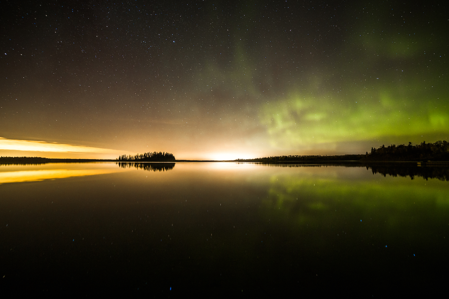 green northern lights over astotin lake in alberta canada