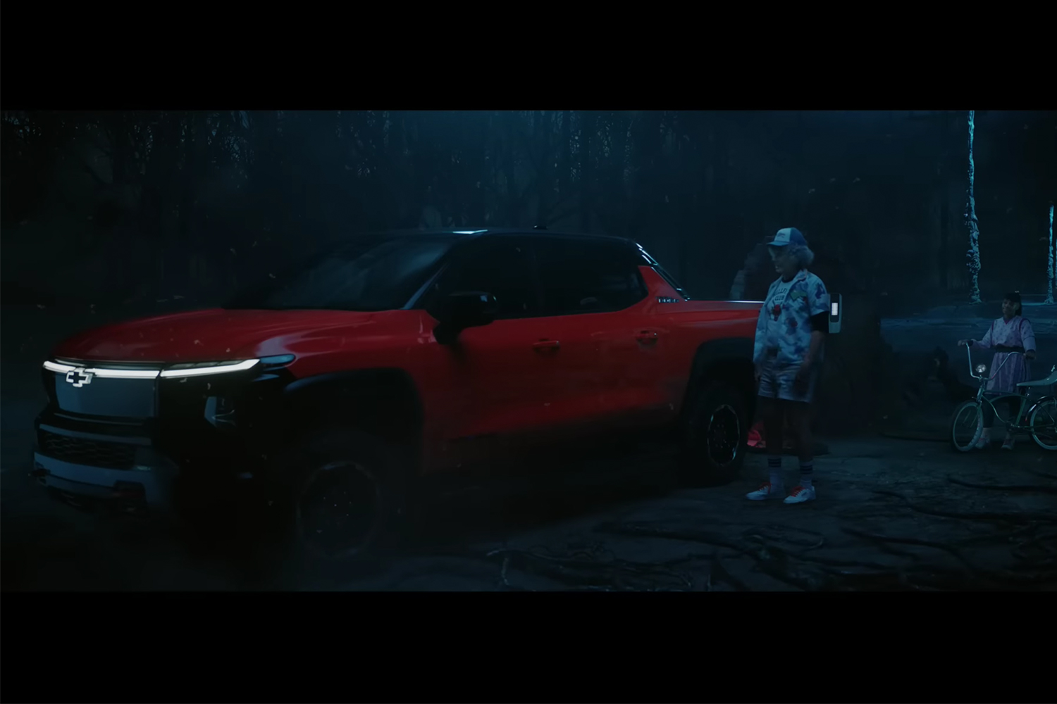 Will Ferrell and Priah Ferguson stand next to a Chevrolet Silverado EV Trail Boss in the Netflix and GM Super Bowl ad for 2023
