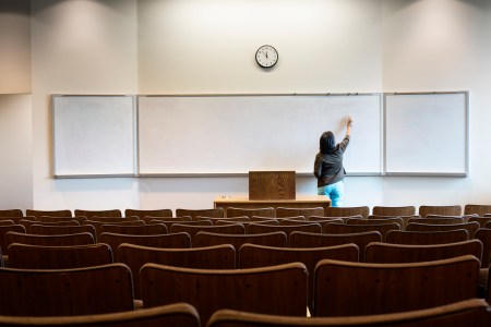 A woman writing on a whiteboard in a lecture hall.