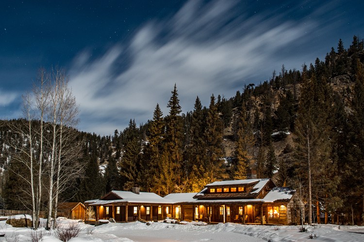 Taylor River Lodge, located in Colorado, pictured here at night covered in snow during the winter