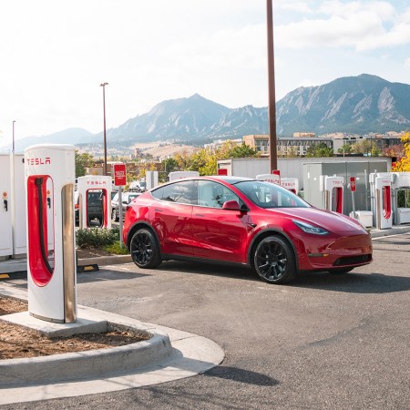 A red Tesla Model Y at a Tesla Supercharger station. Elon Musk said Tesla will open up some of its charging network to other EVs.