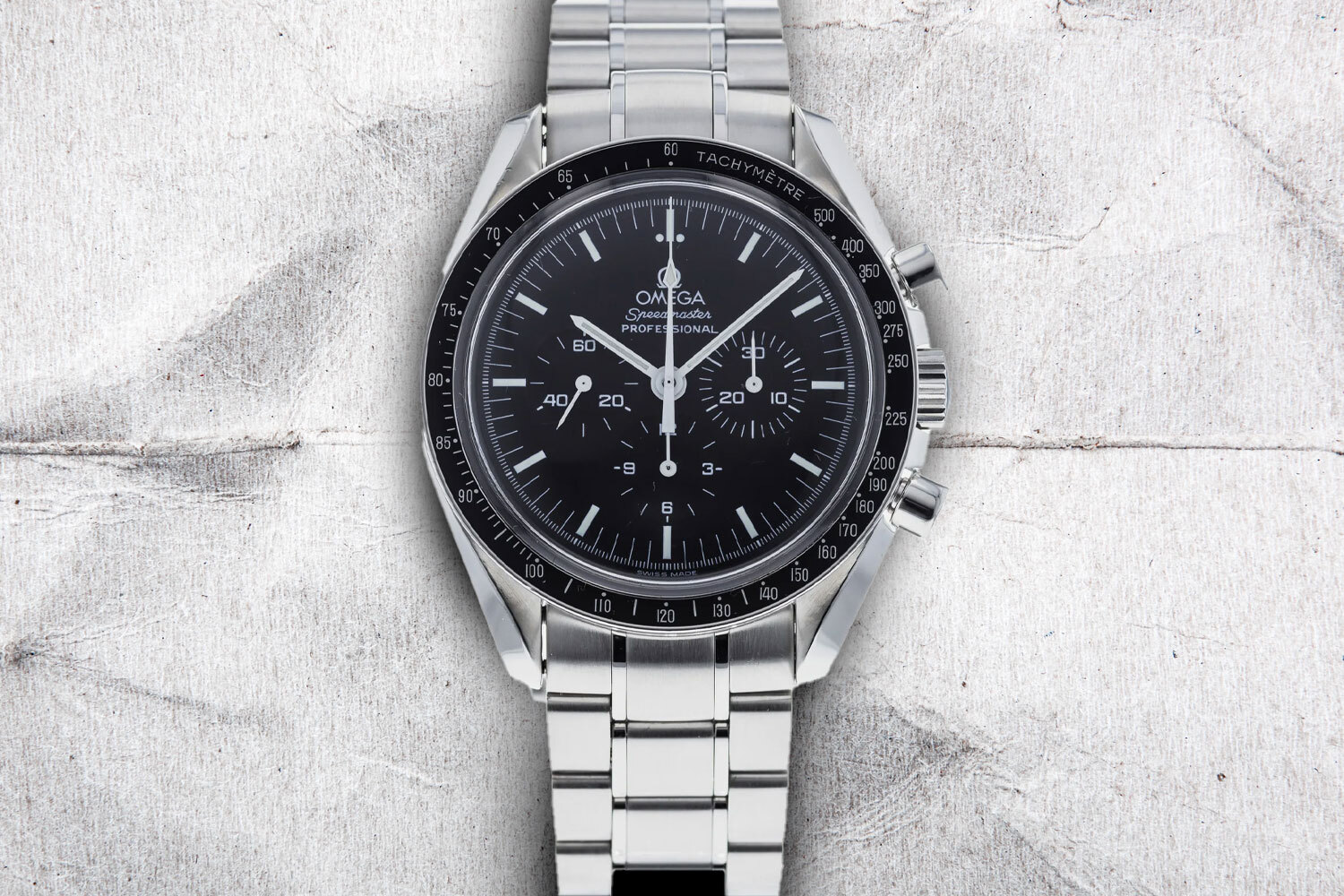 An Omega Speedmaster on a gray background