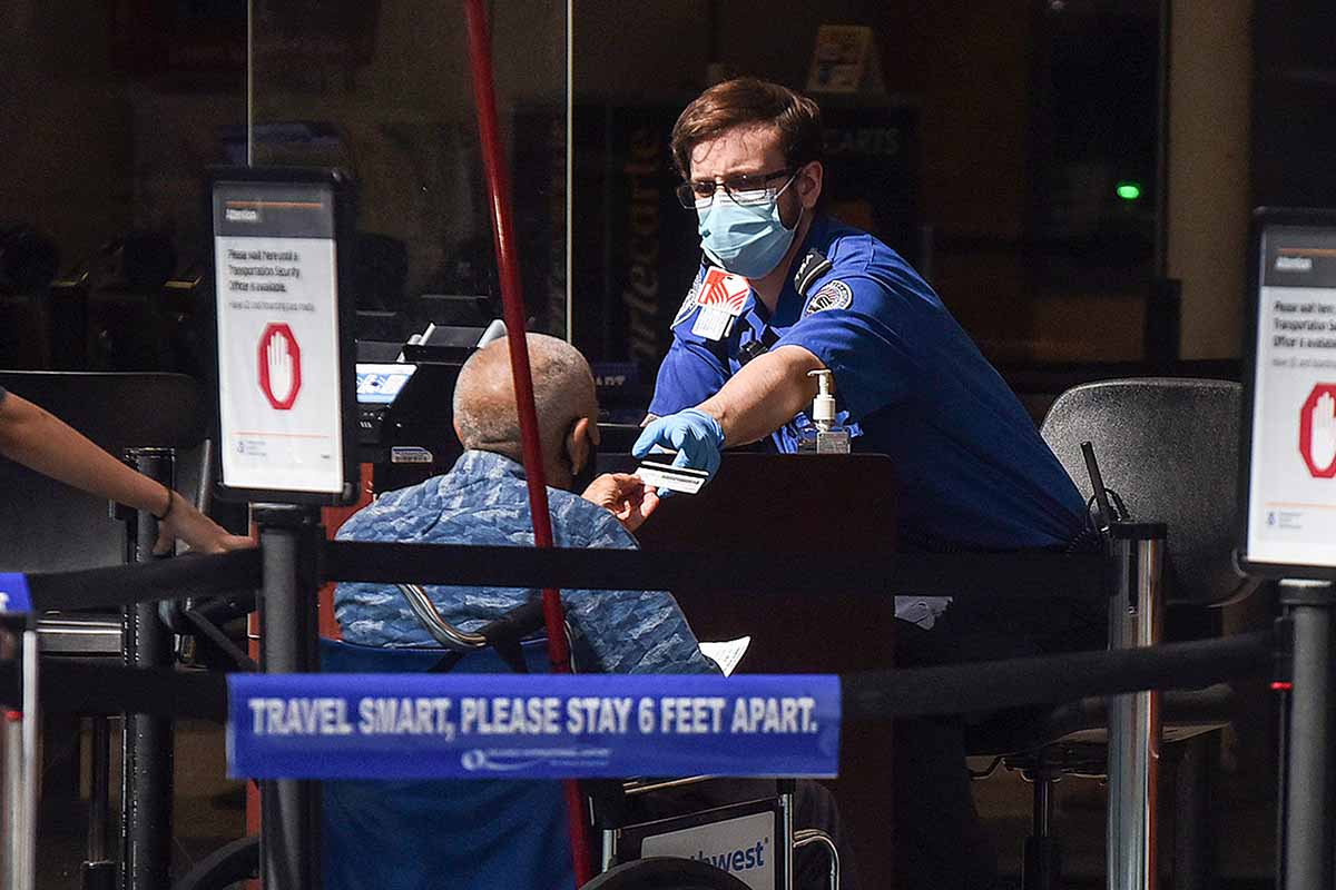 A man in a wheelchair hands his ID to a TSA officer at a screening checkpoint at Orlando International Airport. Some Twitter conjecture suggests passengers are faking the need for wheelchairs to get on board early.