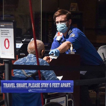 A man in a wheelchair hands his ID to a TSA officer at a screening checkpoint at Orlando International Airport. Some Twitter conjecture suggests passengers are faking the need for wheelchairs to get on board early.