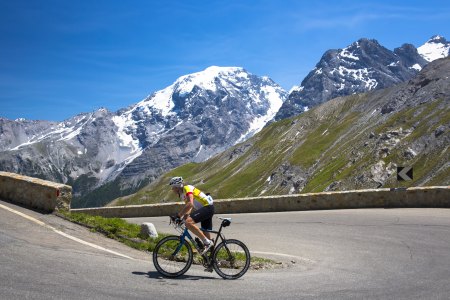 A cyclist going up a hill with mountains in the background.