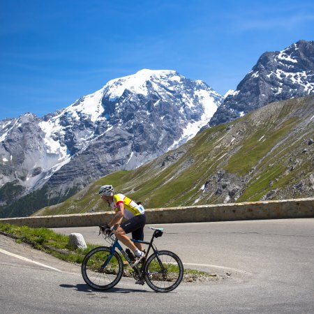 A cyclist going up a hill with mountains in the background.
