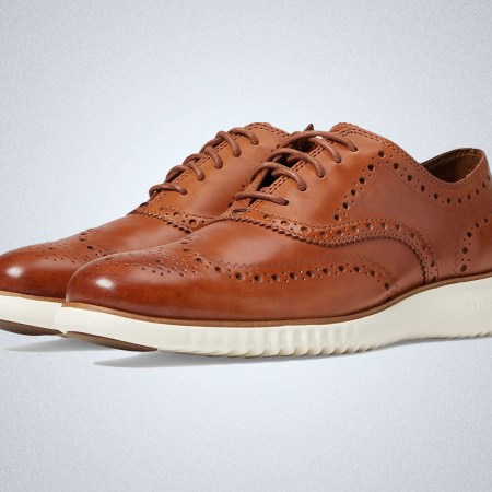 a pair of tan wingtip oxfords from Cole Haan on a grey background