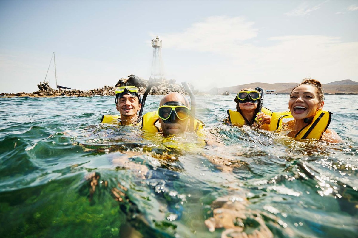 portrait of smiling family on snorkeling tour in tropical ocean while on vacation