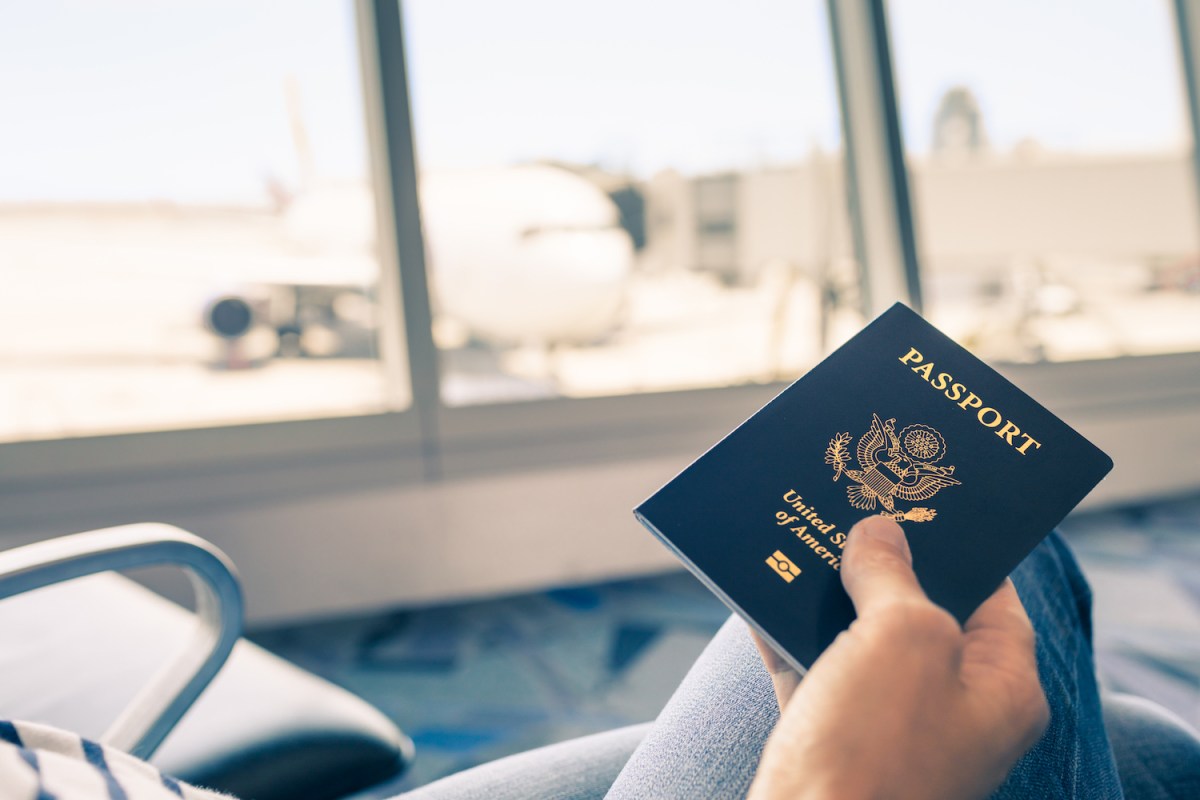 Traveler at airport holding United States passport in hand