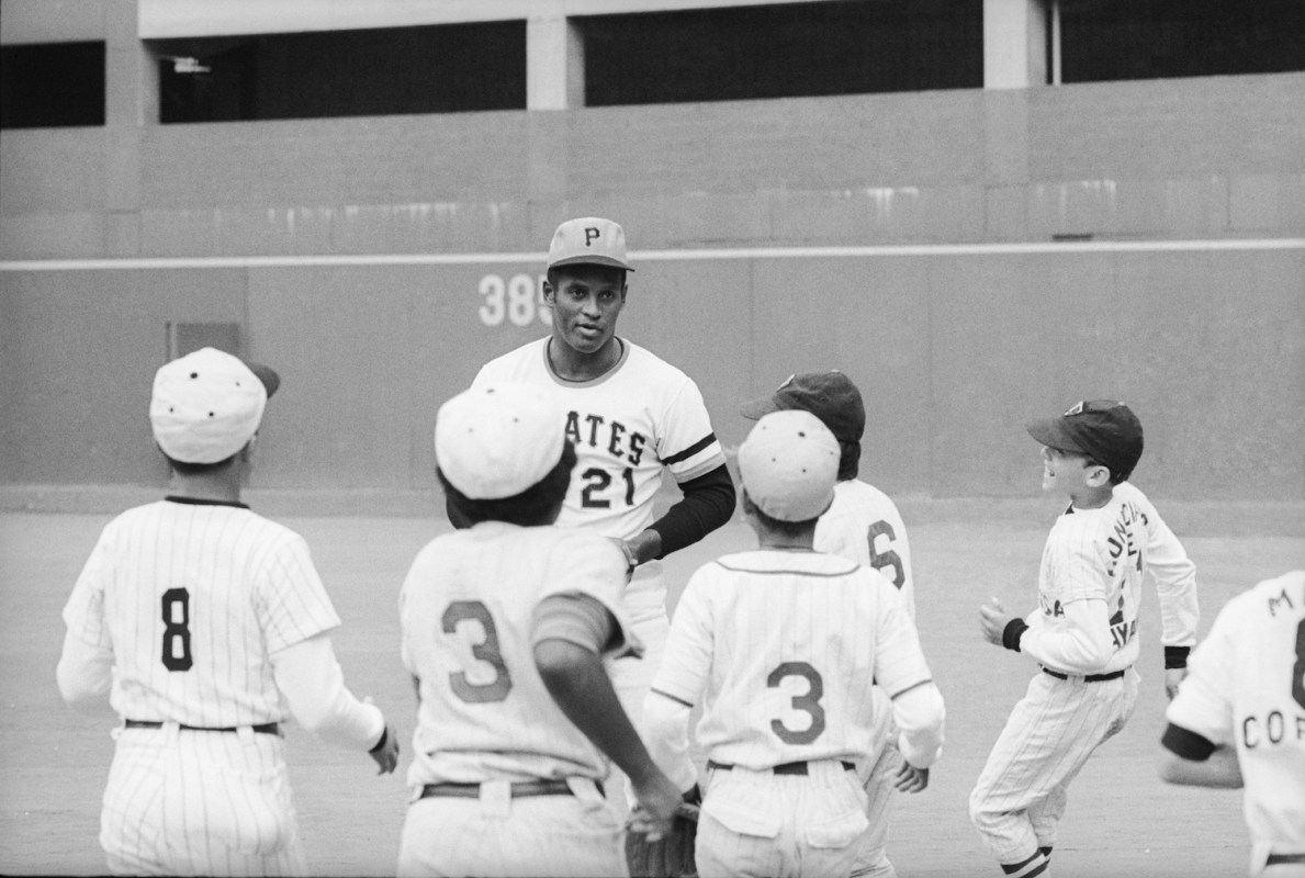 Roberto Clemente talks with kid ballplayers at his home field