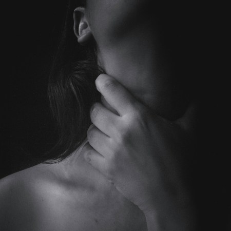 Midsection Of Topless Woman Choking Throat Against Black Background