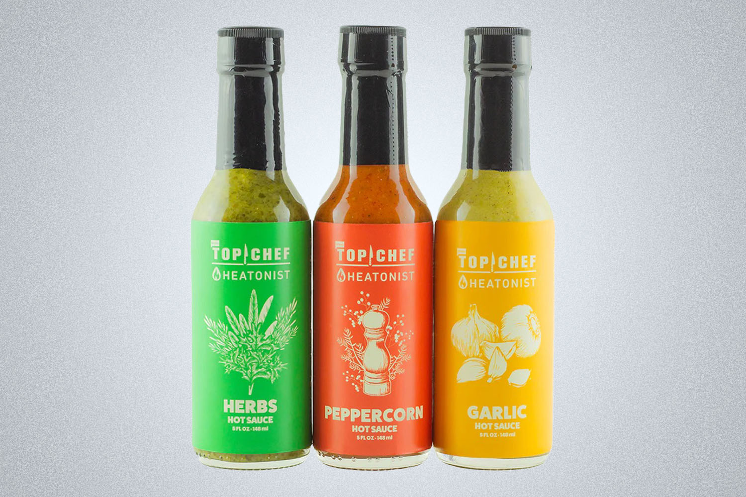 a trio of Heatonist Top Chef hot sauces on a grey background
