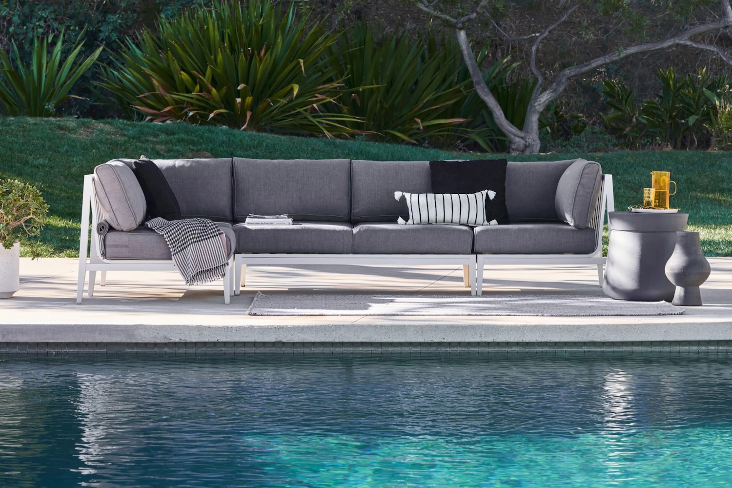 White Aluminum Outdoor Sofa with Dark Pebble Gray Cushions in front of a pool