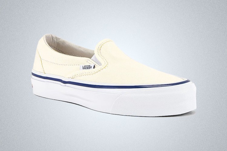 a pair of white Vans Slip-On Shoes on a grey background