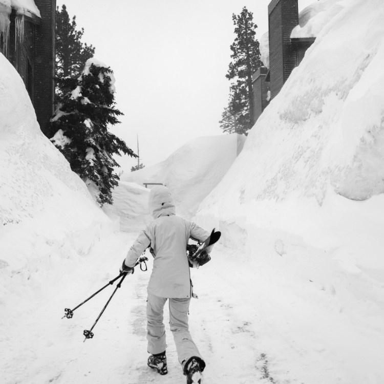 a black and white photo of someone carrying their skis through the Snow