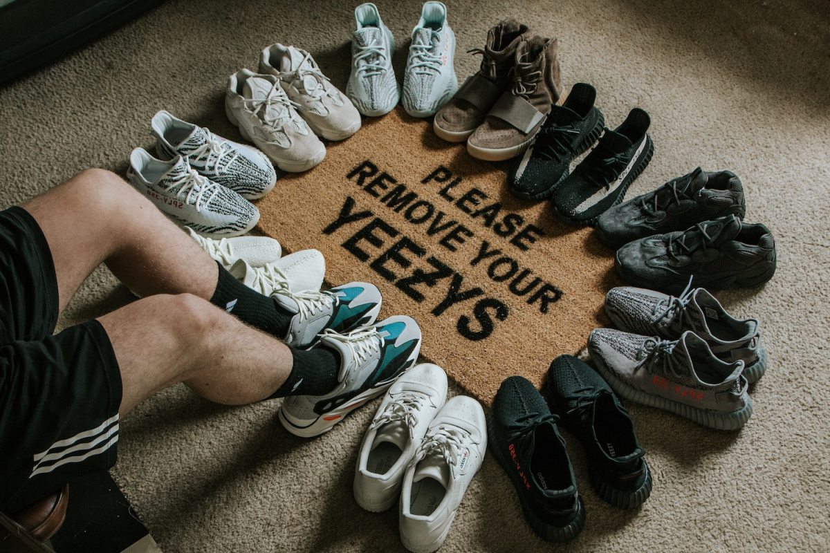 Pairs of Yeezy sneakers circle a welcome mat that says "Please Remove Your Yeezy's" on the floor