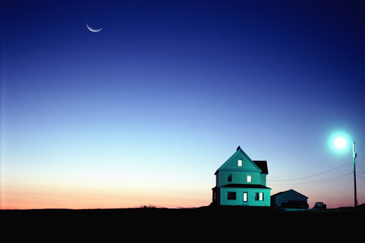A house at dusk with the moon in the background.