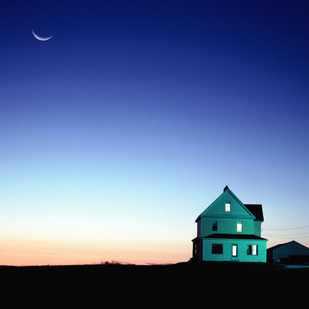 A house at dusk with the moon in the background.